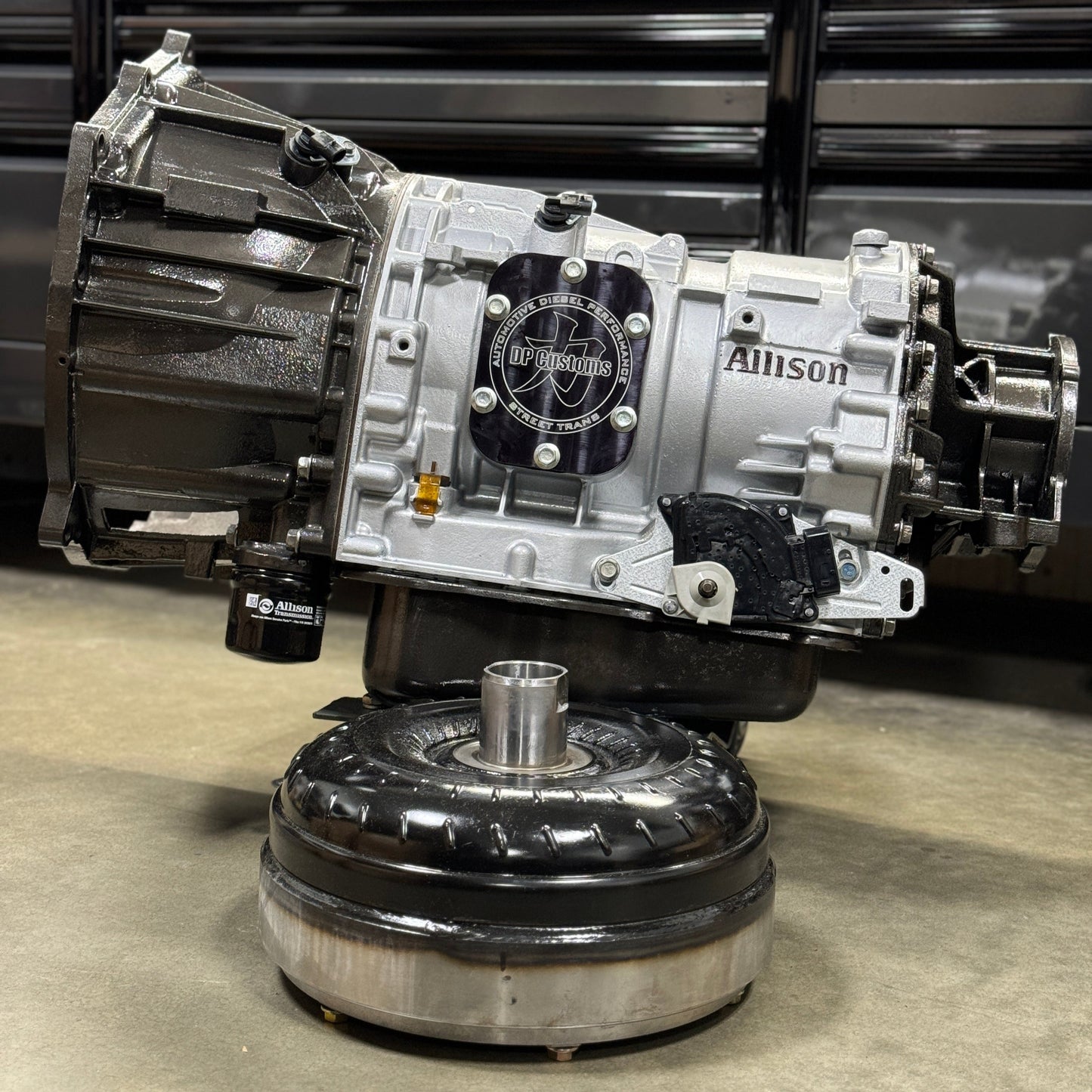 DP Customs Allison 750hp Street Transmission showing metal casing, gear components, and hydraulic linkages.