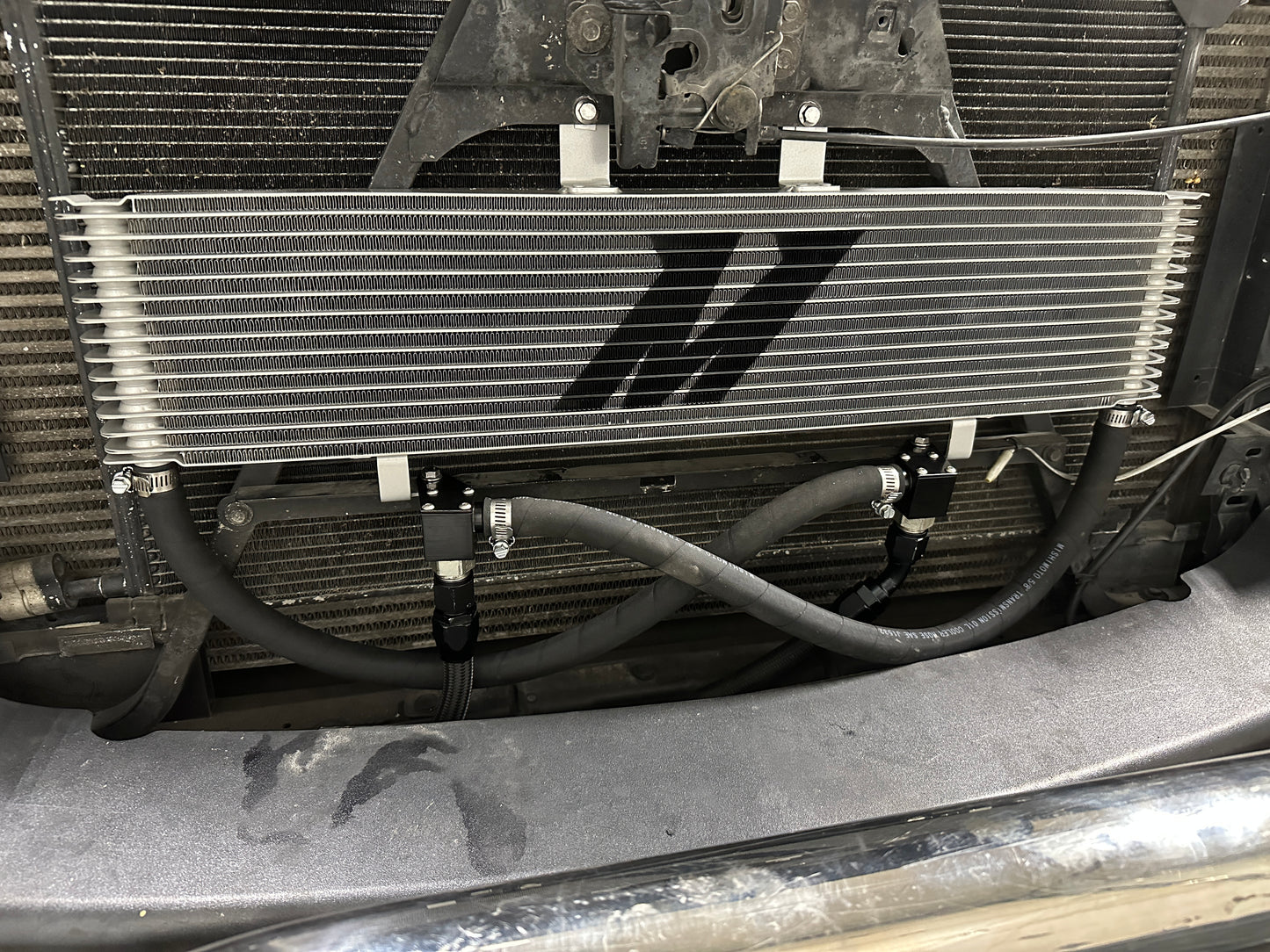 Mishimoto Duramax/Allison transmission cooler with metal fins and hoses for efficient cooling of transmission system.
