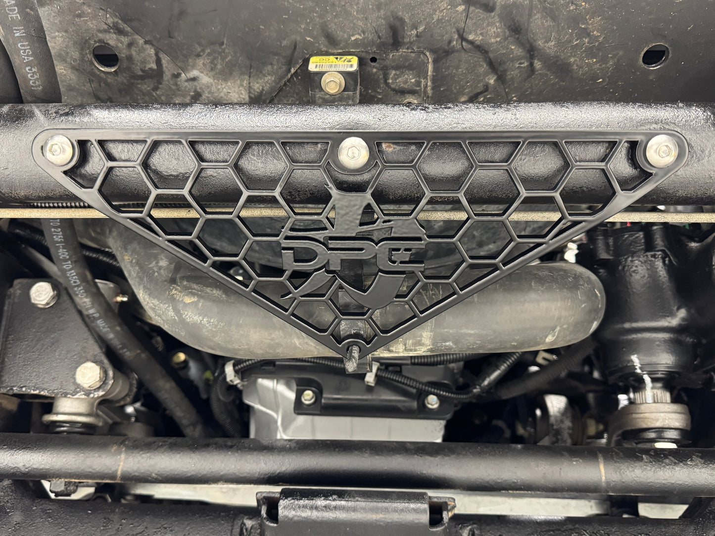 DP Customs radiator hose support bracket for 2001-2010 Duramax engine, metal component with mounting points and hardware.