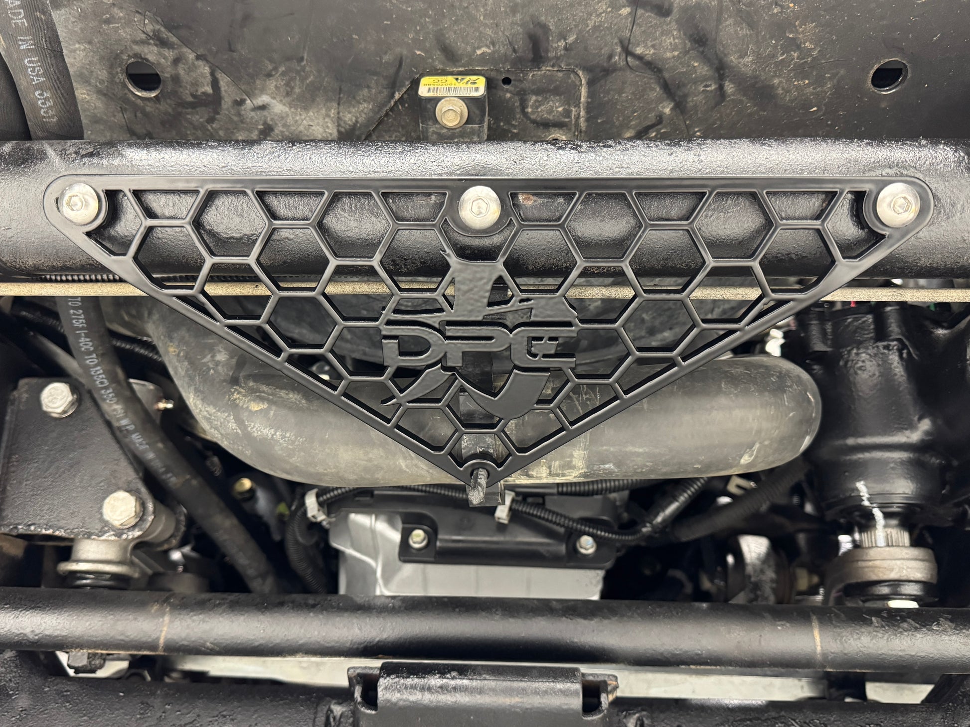 DP Customs radiator hose support bracket for 2001-2010 Duramax engine, metal component with mounting points and hardware.
