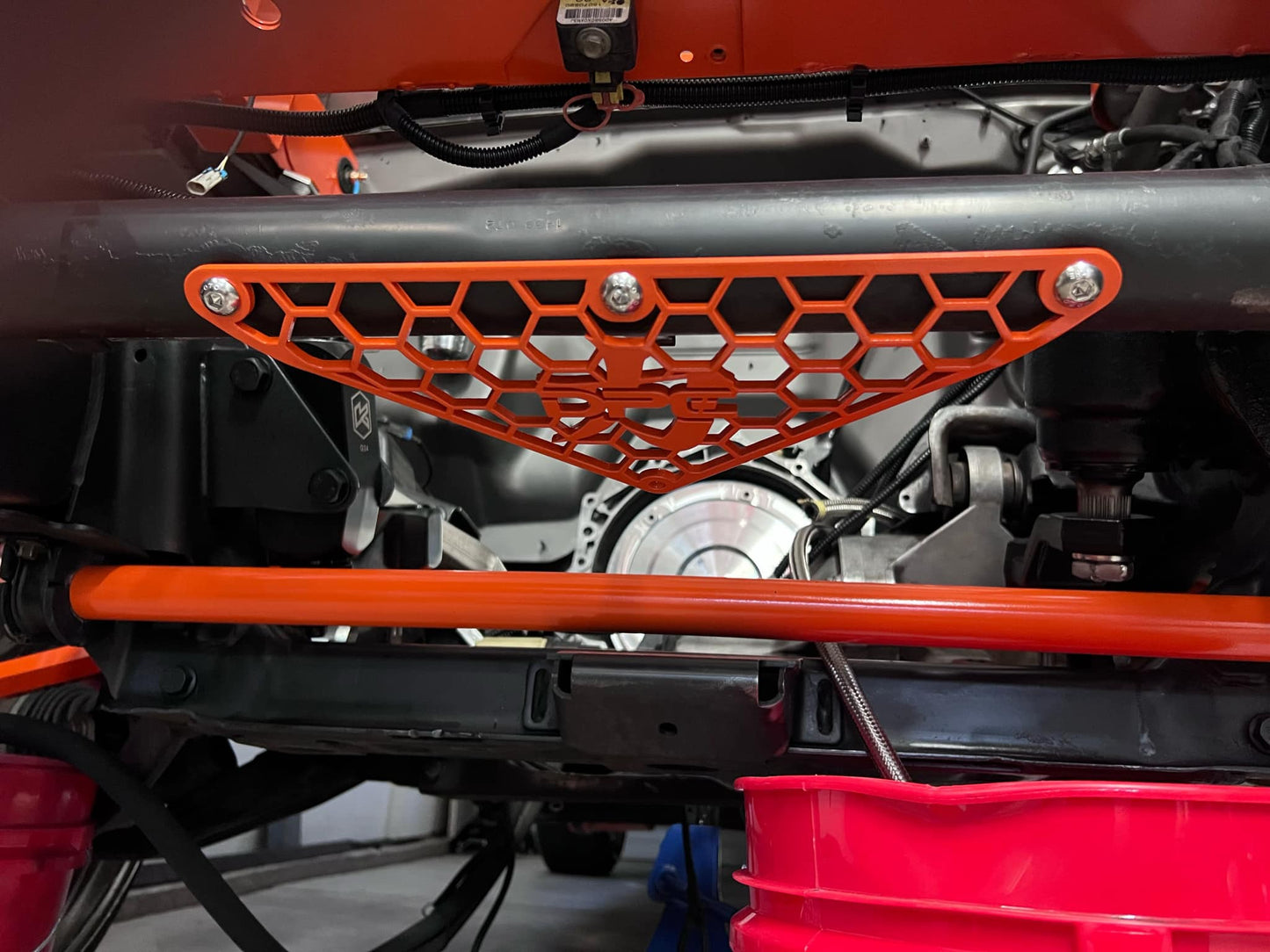 DP Customs 2001-2010 Duramax radiator hose support bracket, black metal part with mounting holes for engine cooling system.