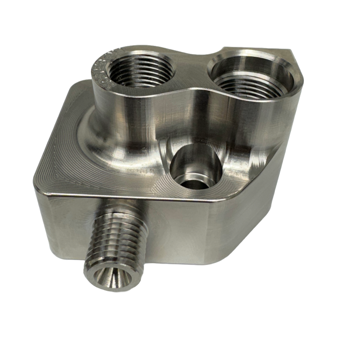 DP Customs LB7 Fuel Distribution Block showing metal fittings and ports for vehicle fuel system connections.