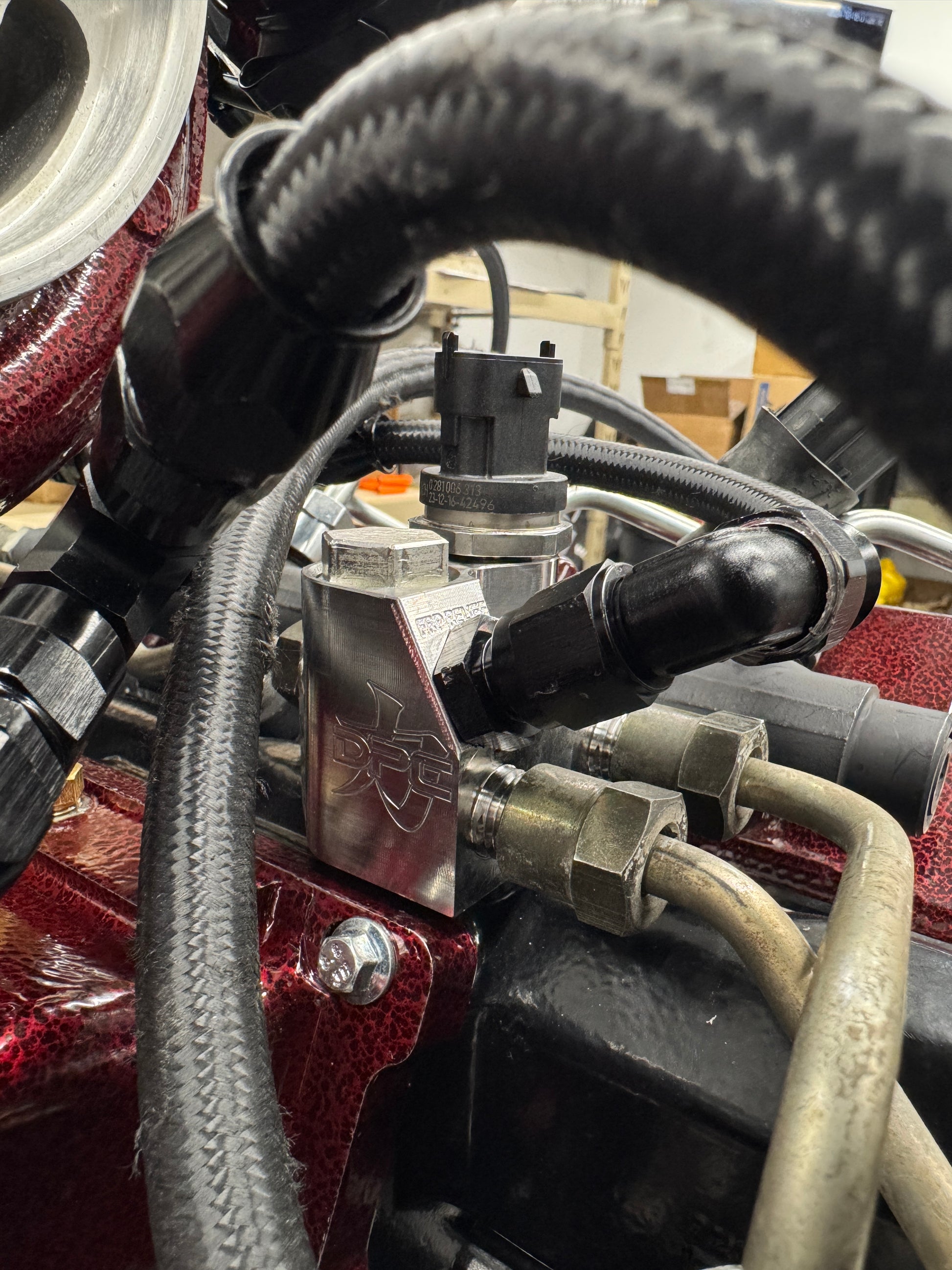 DP Customs LB7 fuel distribution block showing metal fittings and black housing, used for fuel system connections.