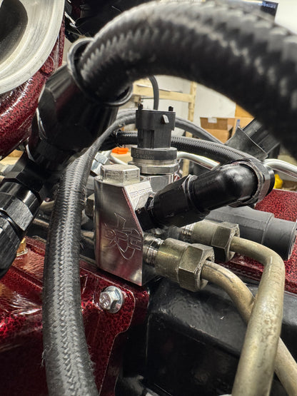 DP Customs LB7 fuel distribution block showing metal fittings and black housing, used for fuel system connections.