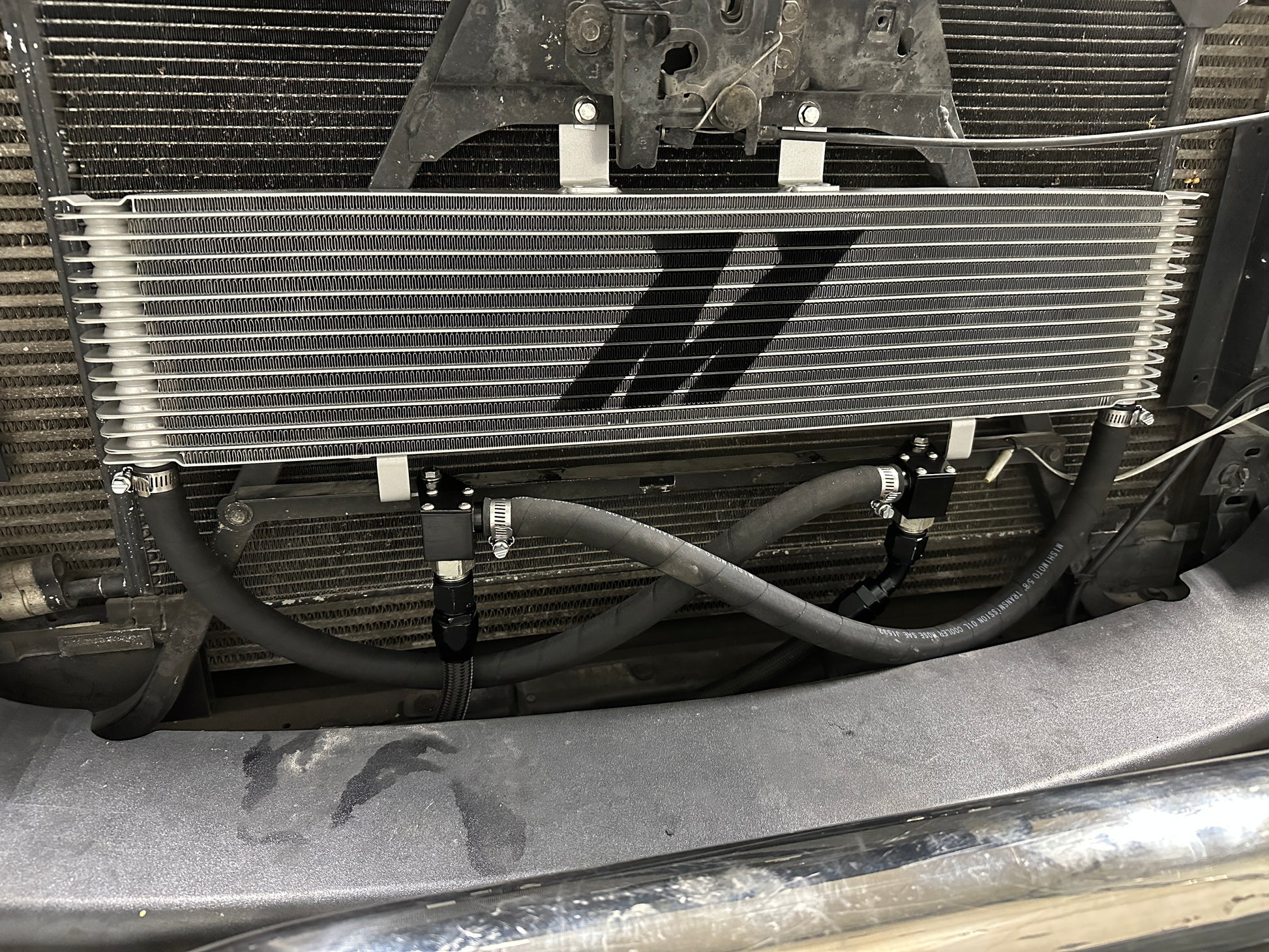 Mishimoto Duramax/Allison transmission cooler with metal fins and hoses for efficient cooling of transmission system.