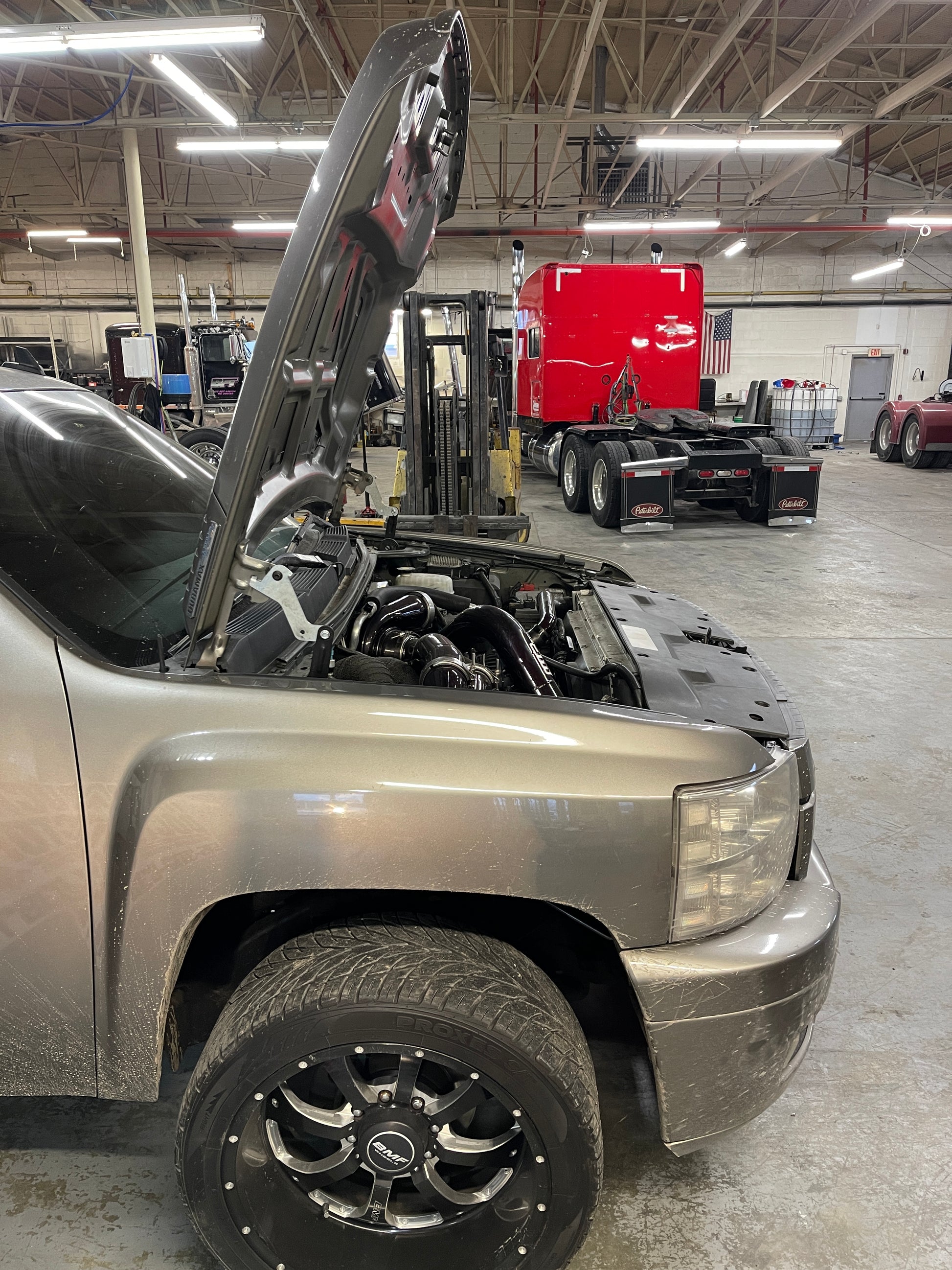 DP Customs High Access Hood Brackets installed on a 2007.5-2016 GM truck, showing sturdy metal brackets for easy hood access.