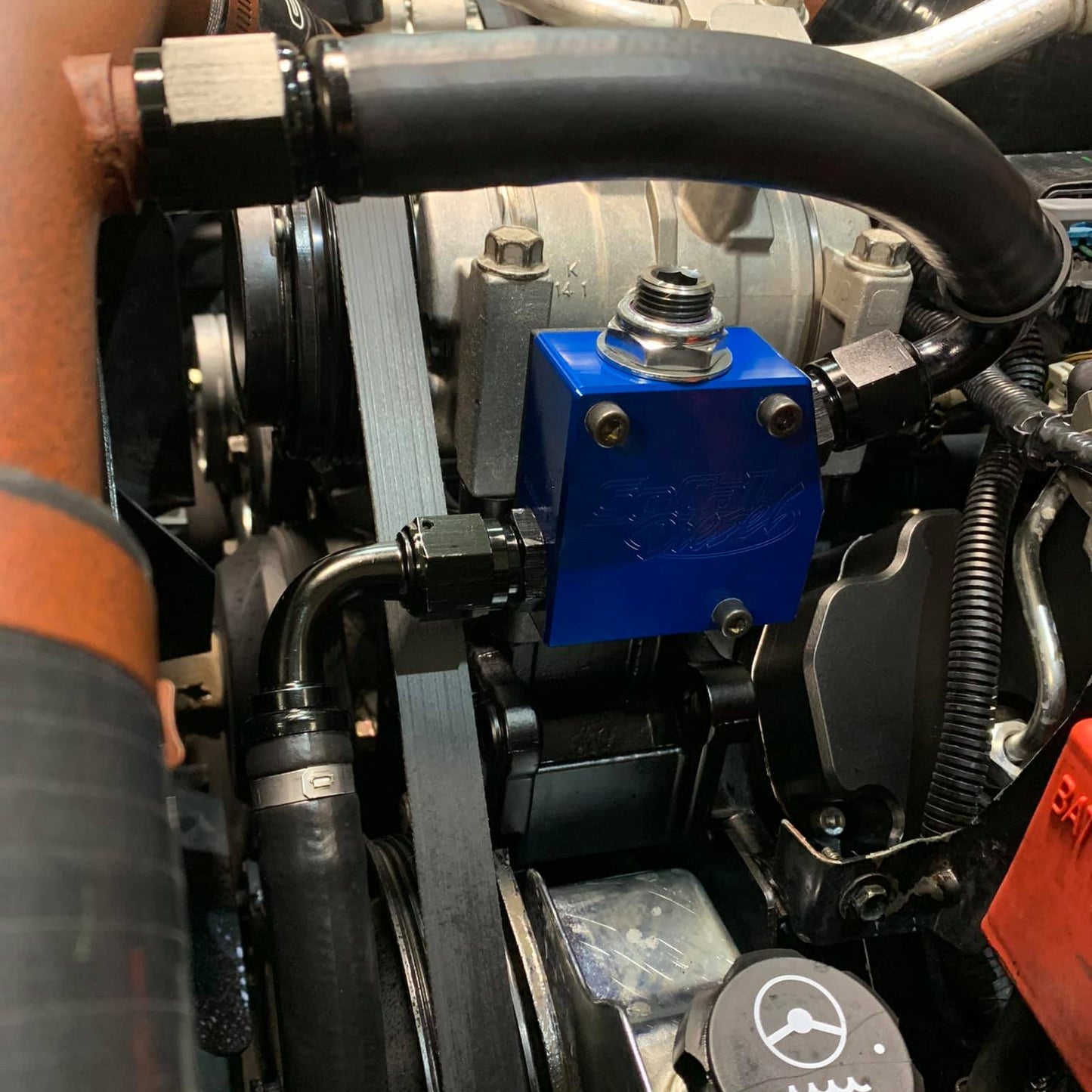 DP Customs SoCal Diesel waterpump bypass bracket mounted on engine component, showcasing durable metal construction for diesel applications.